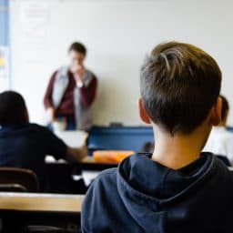 Behind view of children sitting in a classroom setting.