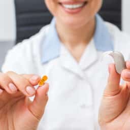 Audiologist holding up a hearing aid.