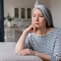 Woman with a sad expression sitting alone at home.