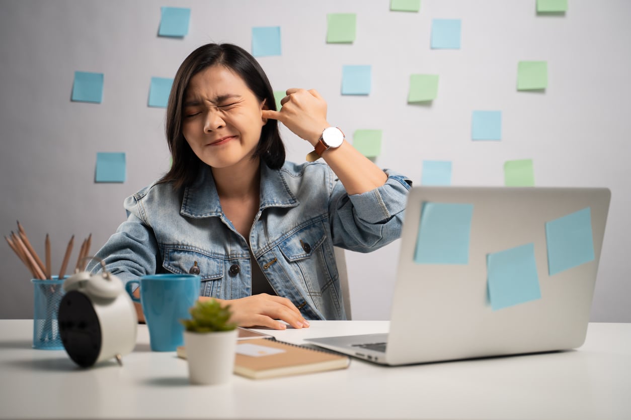 Woman plugging her ear trying to drown out tinnitus
