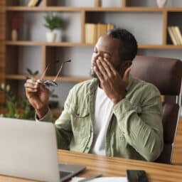 Tired man rubbing his eyes at his computer