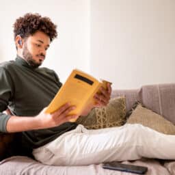 Man with hearing aids listening to an audiobook and reading the physical book
