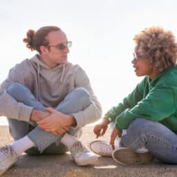 Two people sitting on a sunny beach chatting